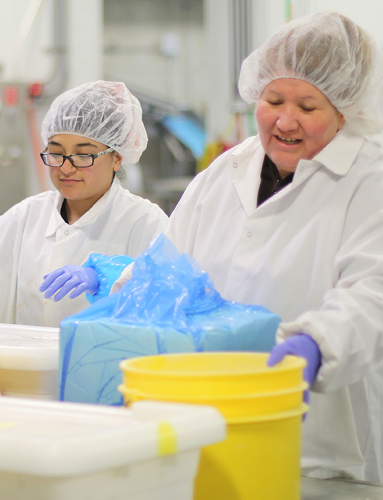 Two production employees mixing together various ingredients