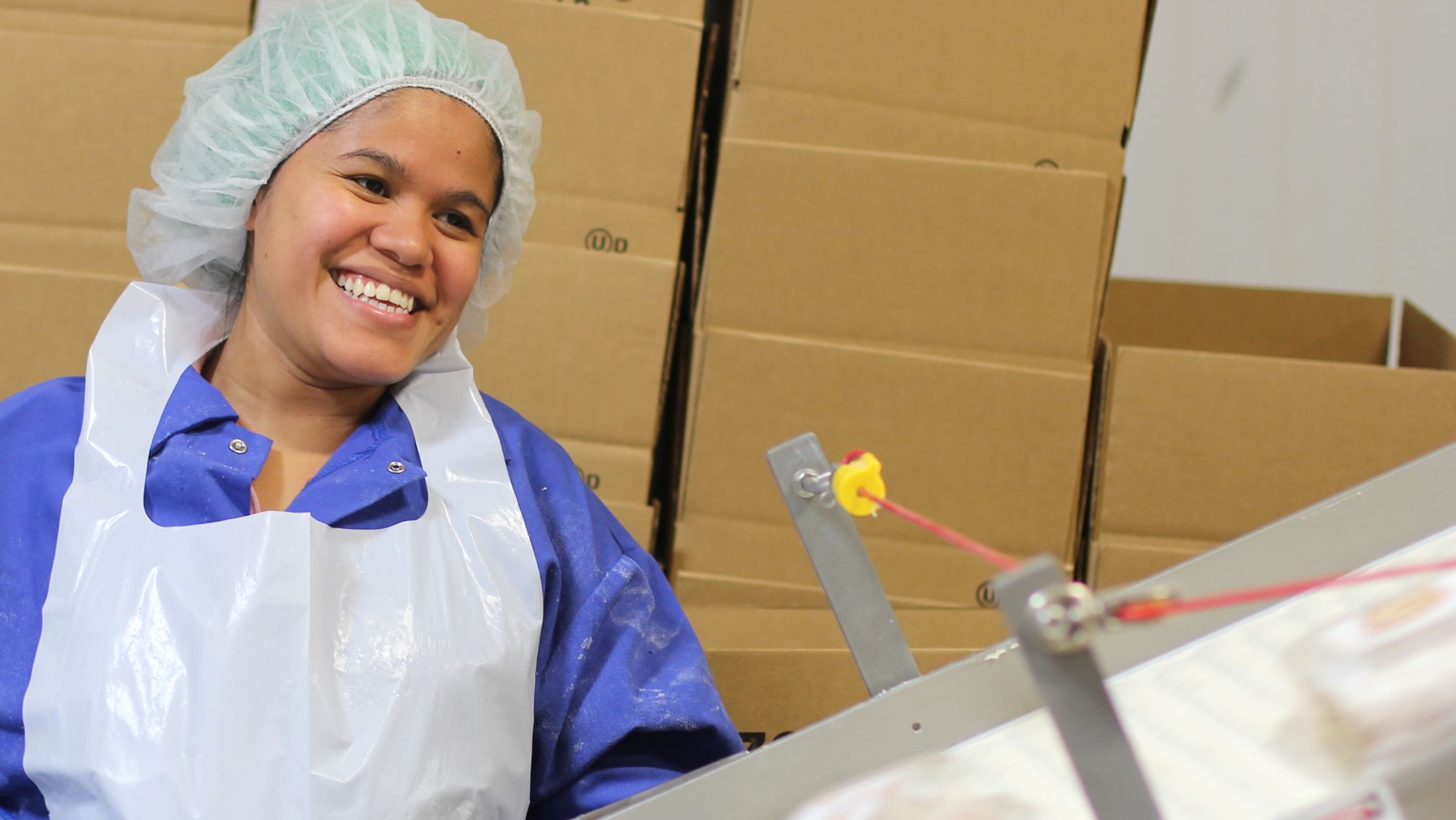 Production employee smiling while packaging product
